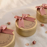 La Vie en Rose Golden Floral Candle made from natural soy wax in a golden candle tin with a soft pink bow and soft floral scent. La Vie en Rose Golden Floral Candle van natuurlijke sojawas in gouden candle tin met roze strik en zachte bloemige geur.